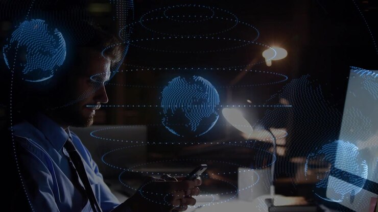 Male tech worker manipulating smartphone, shifting to keyboard while globe visualizing network data