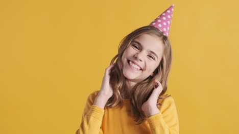 una adolescente caucásica con un sombrero de fiesta y riendo.