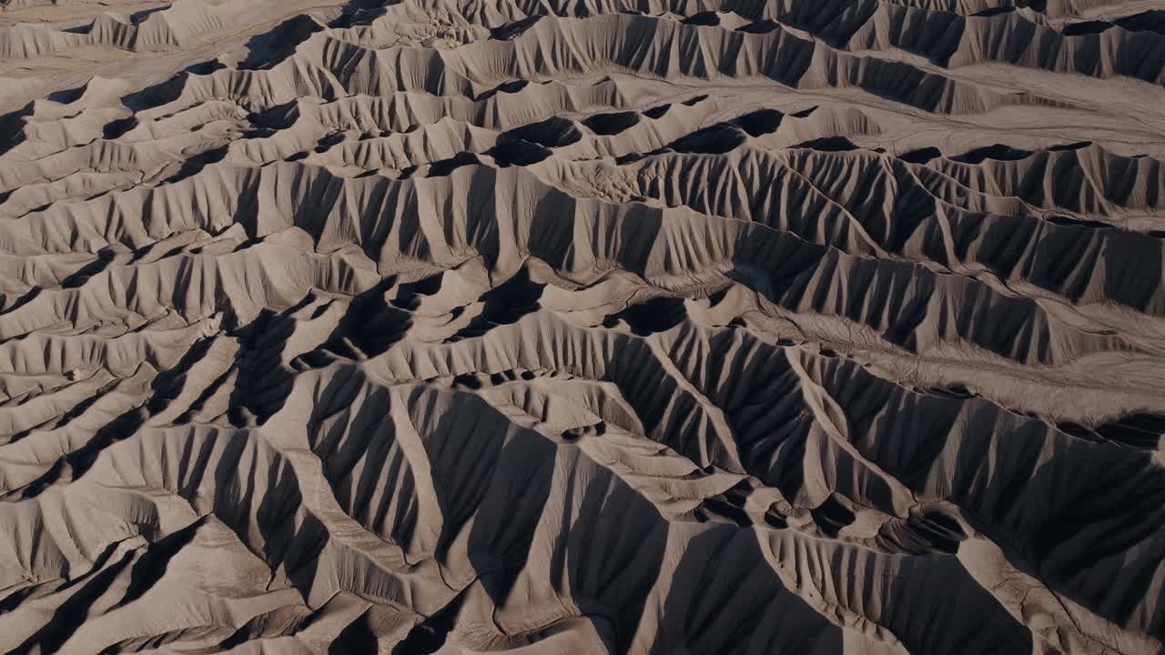 Eroded desert badlands ridges forming textured patterns near Factory Butte Utah arid landscape, drone