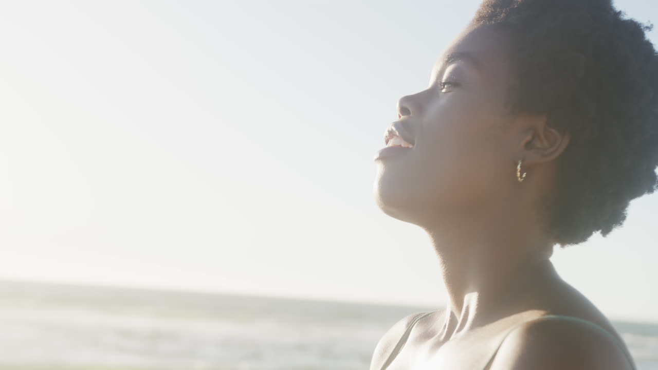 Happy african american woman smiling at beach, in slow motion, with copy space