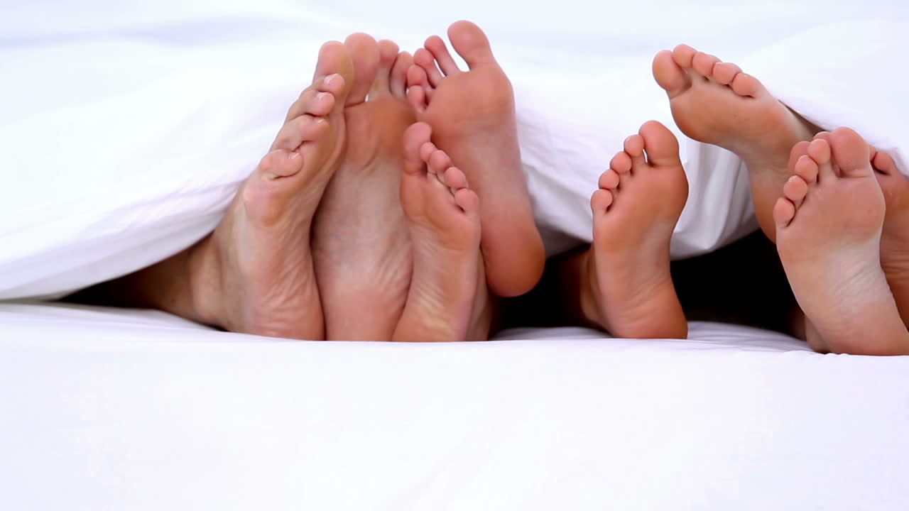 Pies de la familia asomándose por debajo de las sábanas