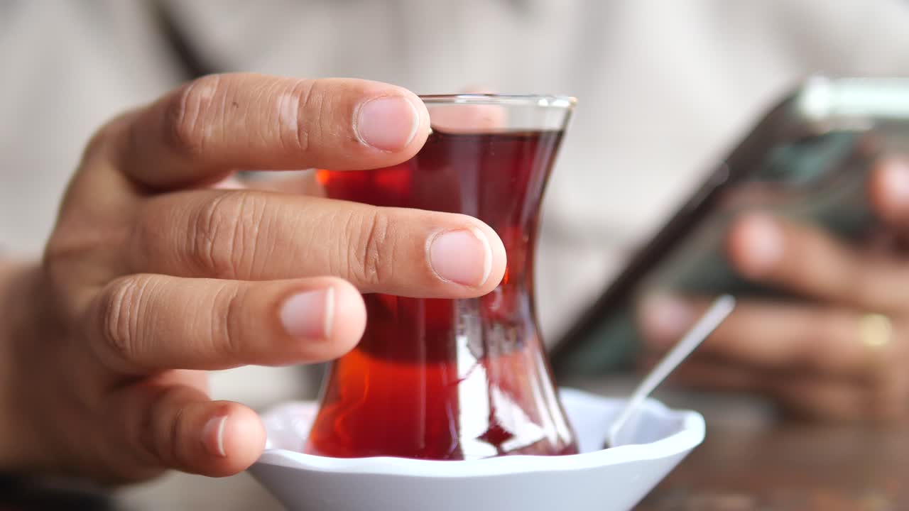 Person holding a glass of Turkish tea