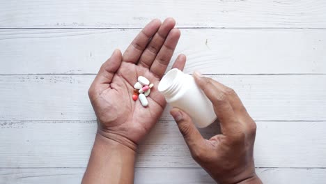 persona que toma pastillas de un frasco blanco
