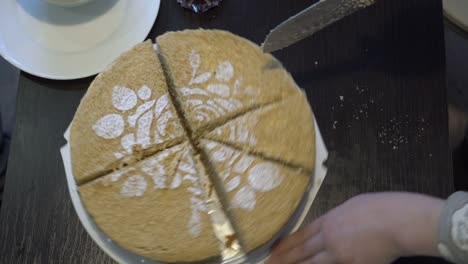 a child, a little girl, cuts a beautiful yellow cake into pieces with a large kitchen knife on a black home table. the concept of a family celebration. close-up. faceless. top view. 4k.