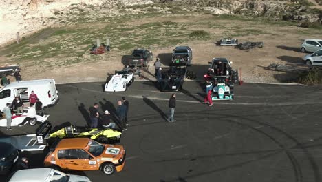 men talking and roaming near the cars parked at the end of the road on the hill in imtahleb malta - aerial shot