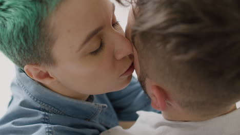 close up of loving woman tenderly cuddling and kissing her boyfriend at home