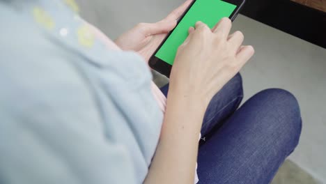 joven asiática alegre sentada en un café usando un dispositivo de teléfono inteligente con pantalla verde para hablar, leer y enviar mensajes de texto. concepto de estilo de vida de las mujeres.