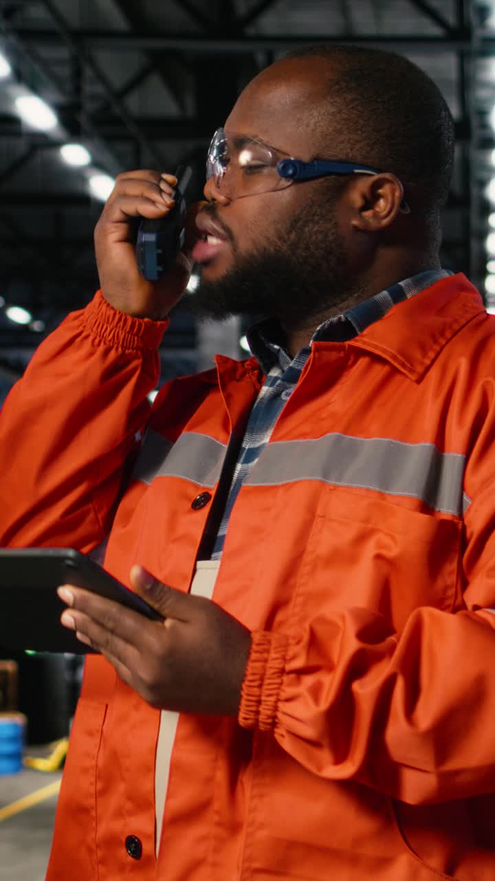 Vertical Video African american professional worker using walkie talkie radio in industry plant