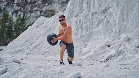 strength training on nature. sportive man exercising with medicine ball at nature