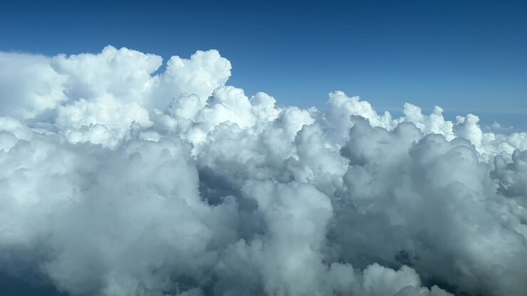 Aerial view from a jet cockpit overflying a sky plenty of white cumulus