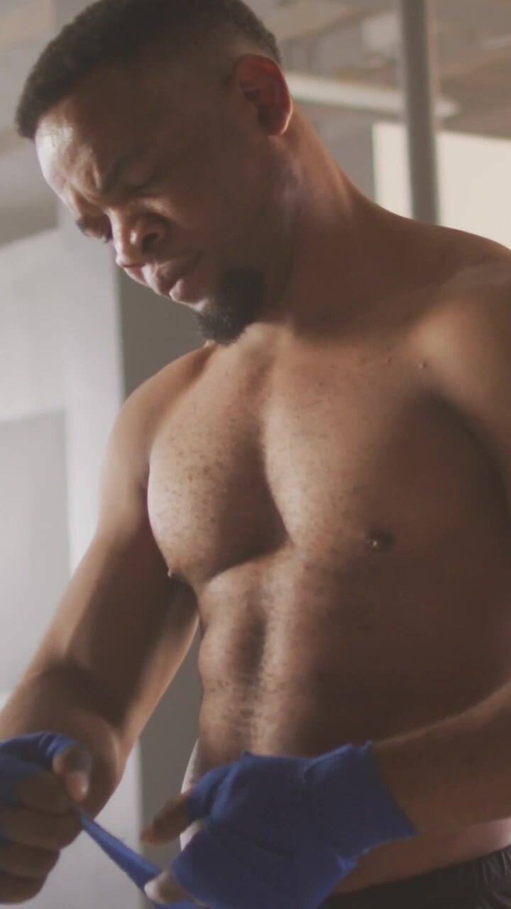 Video verticale: Pugile che si fascia le mani con bende blu, preparandosi per la boxe, barre e linee che si muovono su viso e busto