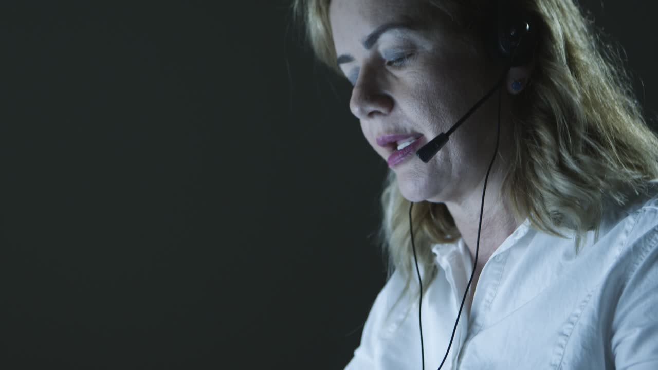 Fokusert forretningskvinne med headset som bruker bærbar datamaskin