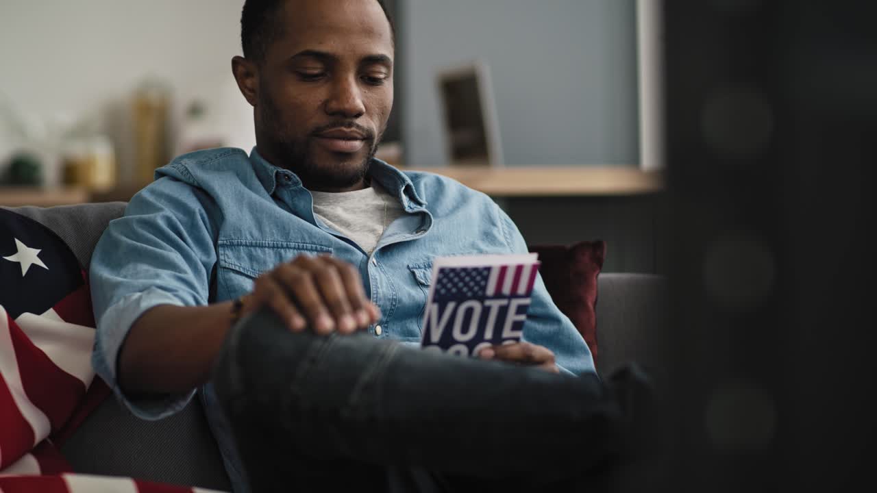 Handheld video of content black man watching TV