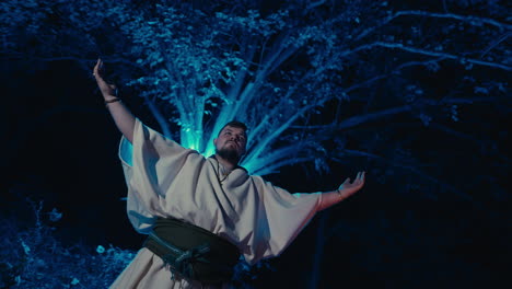 man in medieval costume performing in forest at night