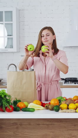pretty woman standing in kitchen. young woman playing with fruits in the kitchen vertical video
