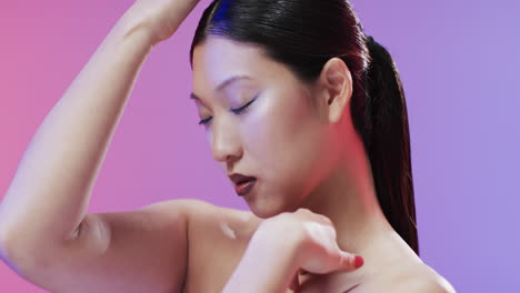 asian woman with black hair and make up touching her face, copy space, slow motion