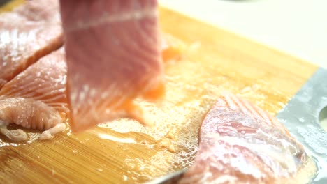 close-up of a chef slicing fresh salmon fillet on a wooden cutting board