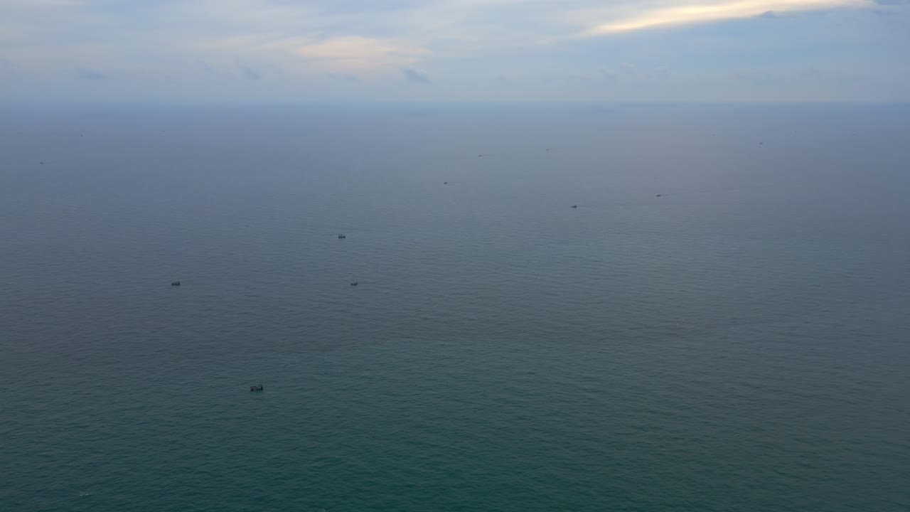 A fleet of fishing boats appears as tiny dots scattered across a vast, open ocean.
