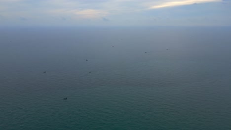 A fleet of fishing boats appears as tiny dots scattered across a vast, open ocean.