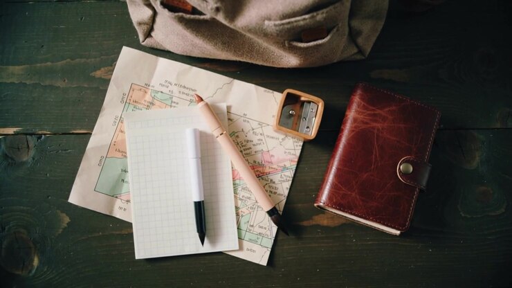Fermeture éclair avant s'ouvrant sur un sac à dos beige, révélant une fiche et une carte sur une table, stylos s'alignant pour le voyage