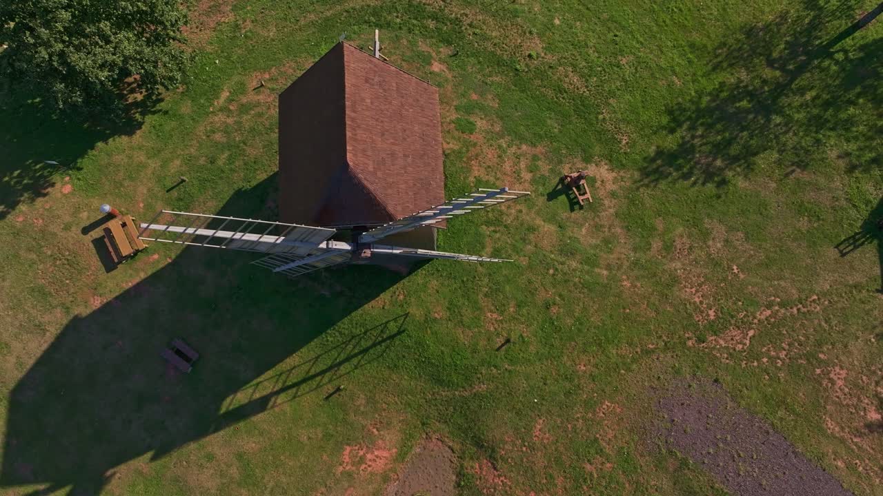 Ripresa aerea di un mulino a vento storico tra alberi rigogliosi, Borovnice