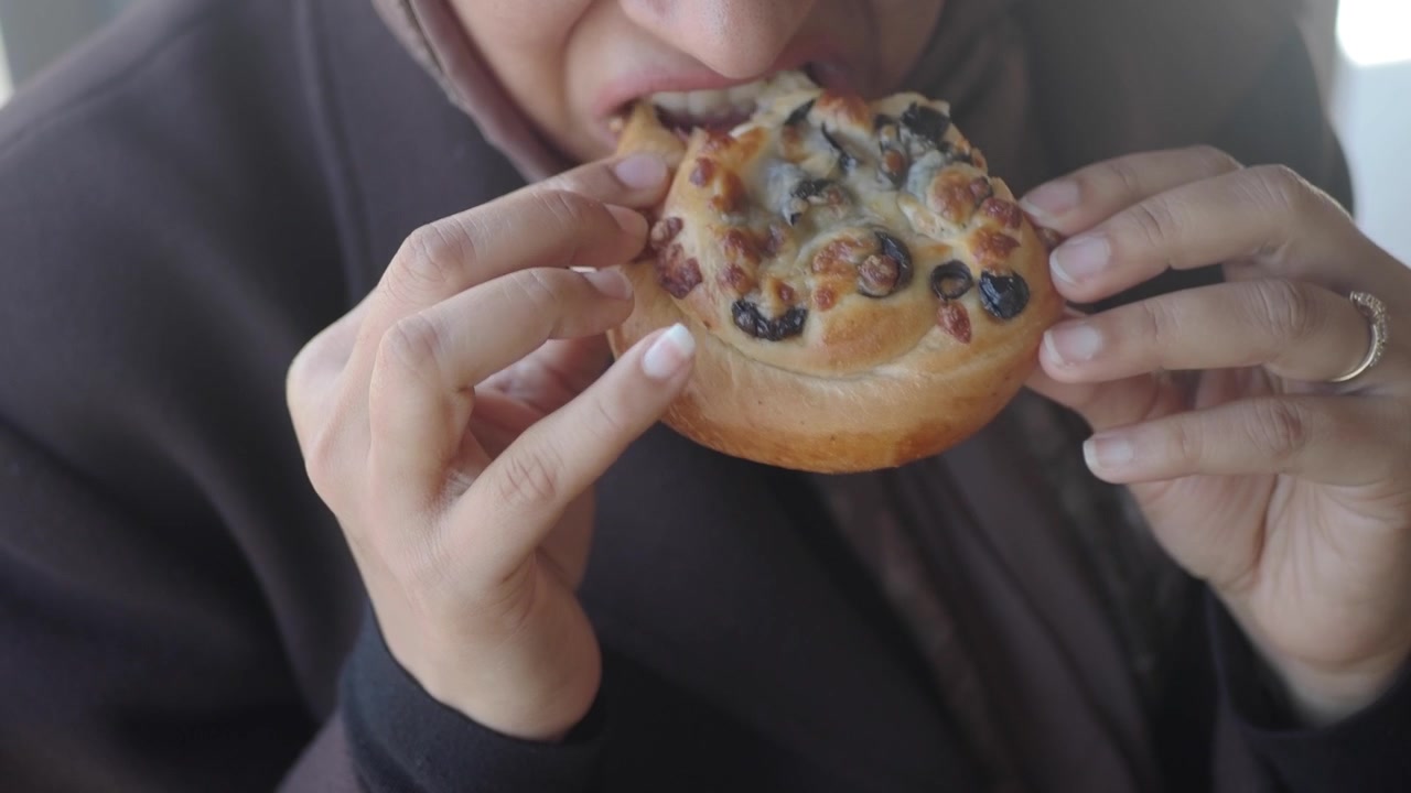 Woman Eating a Savory Pastry with Olives and Cheese