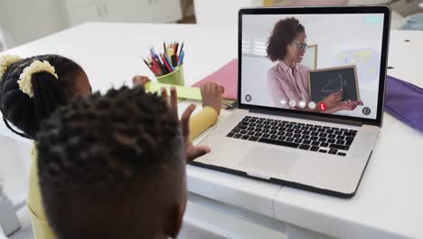 African-american-siblings-having-class-during-laptop-video-call-with-female-teacher-in-slow-motion