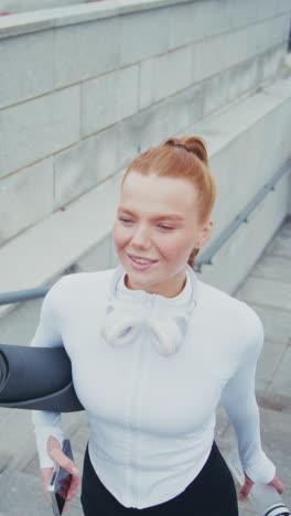 a fitness enthusiast steps confidently up the stairs, holding a yoga mat and a water bottle, dressed in athletic wear, embodying a healthy and active lifestyle in an urban setting