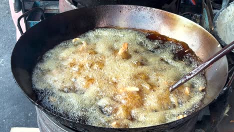 boiling cooking oil in a large pan. frying chicken in thai street food style.