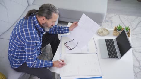 handsome smiling middle aged man sitting on a sofa working on a creative project idea.