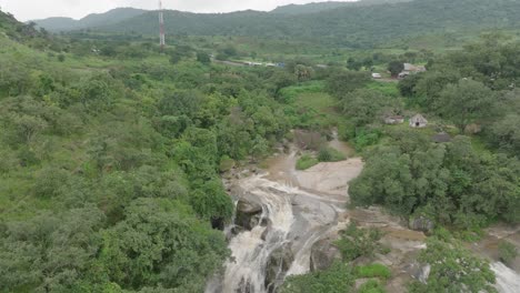 Aerial---Waterfall-in-a-forest-and-hills,-reverse-tilt-reveal