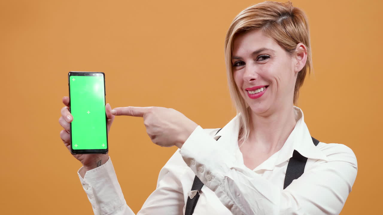 Woman pointing to smartphone with green screen