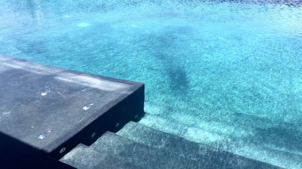 Videoklip af vandbølger i swimmingpoolen i smukt sommerdagslys.