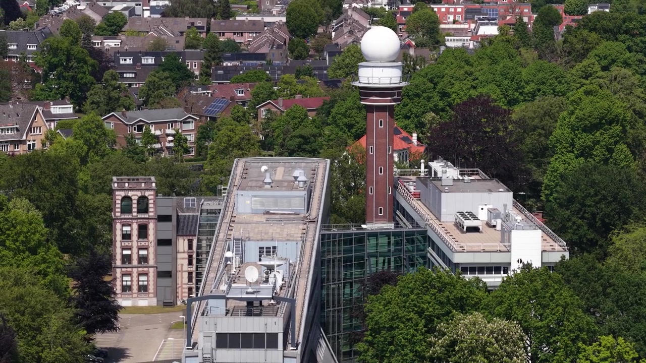 Aerial view of the knmi meteorological institute headquarters featuring the prominent weather radar tower surrounded by lush green trees in the city of de bilt, utrecht, netherlands