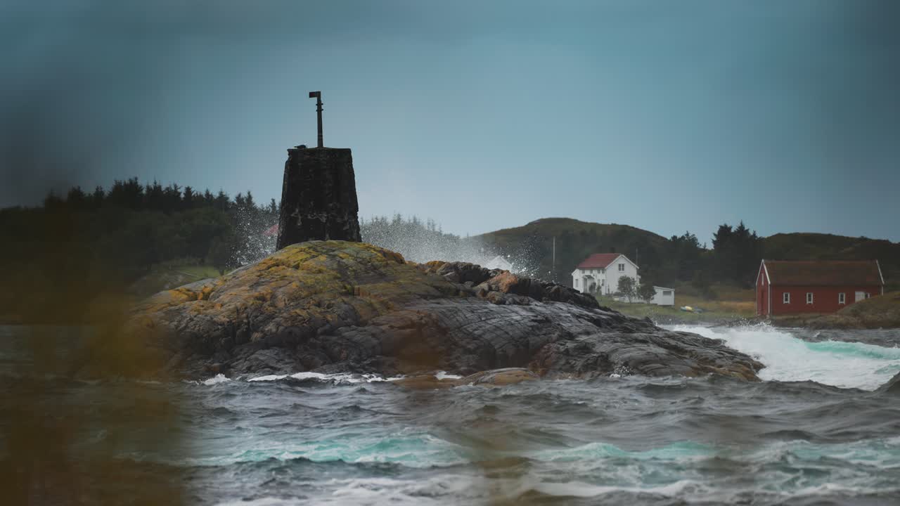 A weathered rocky outcrop rises from the ocean, with coastal homes visible in the background near the Atlantic Road.