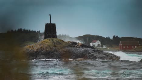 a weathered rocky outcrop rises from the ocean, with coastal homes visible in the background near the atlantic road.
