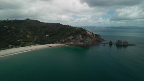 Szenischer-Drohnenflug-Um-Die-Felswand-Auf-Der-Coromandel-Halbinsel-Am-Strand-Von-Otama