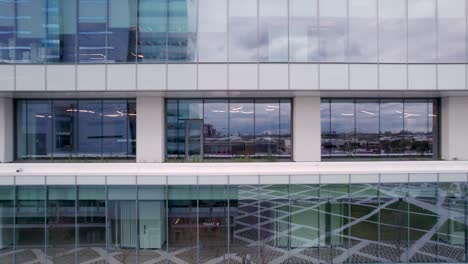 close-up of modern office building facade, reflective glass, opening blinds, drone shot, slow movement