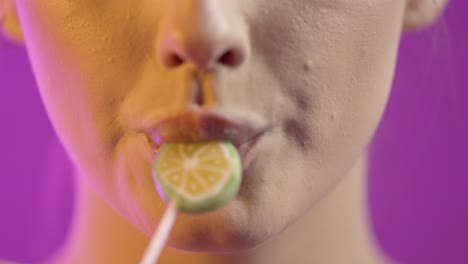 mujer lamendo helado con seducción, boca en primer plano en fondo púrpura