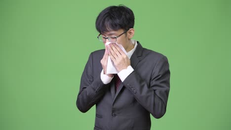 sick young asian businessman blowing nose on tissue