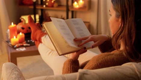 woman reading a book by the fireplace on halloween