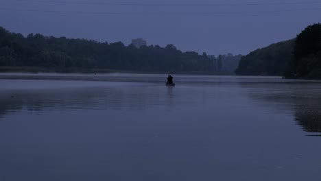 a man floats in a boat on the river at dusk. horror.