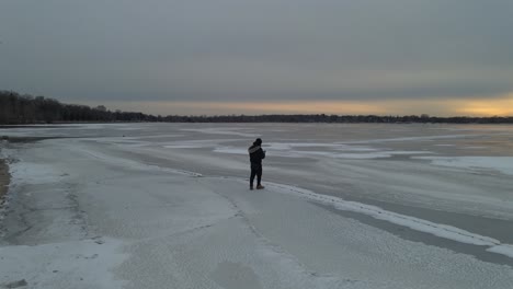 guy walking on ice, frozen lake surface starring at the sunset, explore minnesota