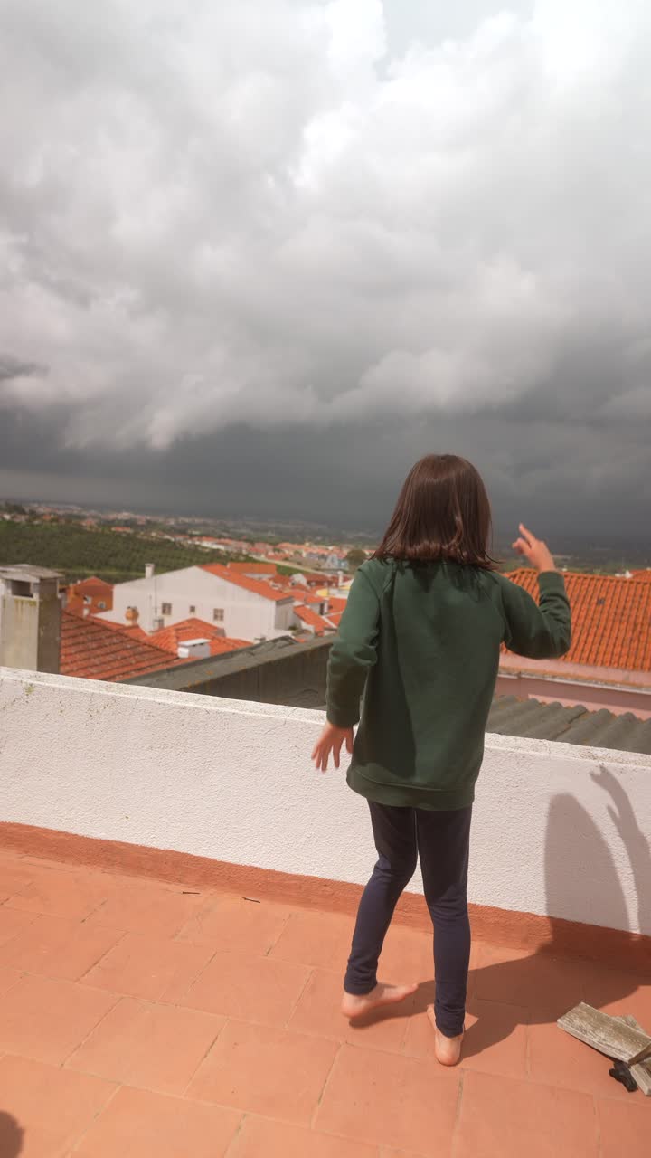 Child Dancing on Rooftop with City View