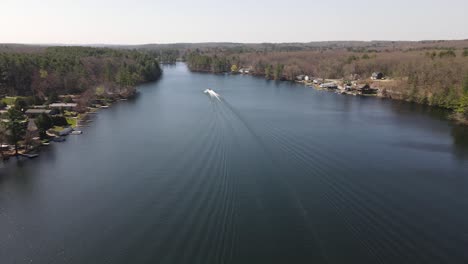 an aerial static view of a watercraft racing down the middle of a large lake