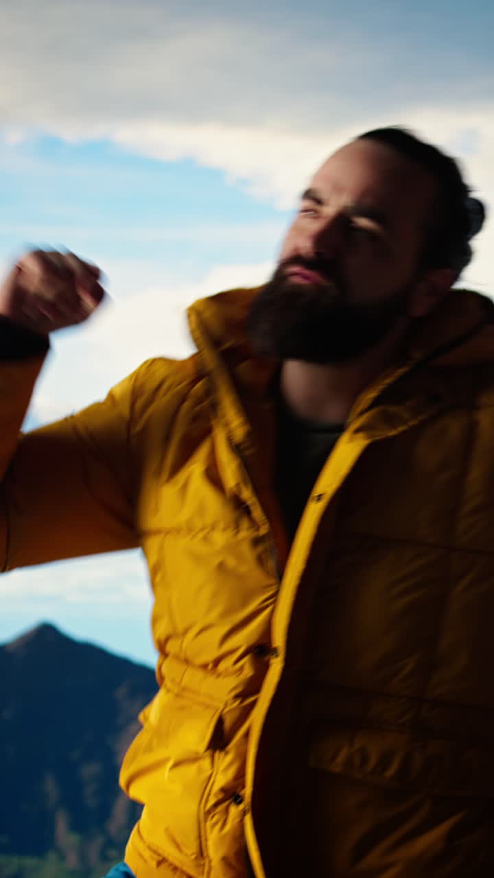 Homem Feliz Dançando Energeticamente no Pico de uma Montanha com um Céu Panorâmico