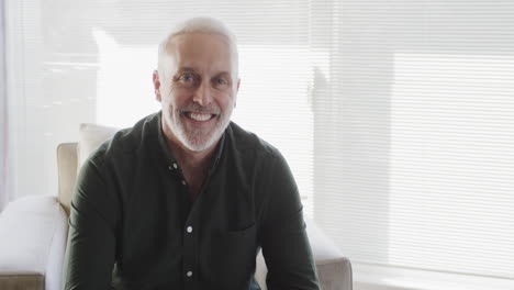 Portrait-of-middle-aged-happy-caucasian-man-sitting-in-living-room-at-home-with-copy-space