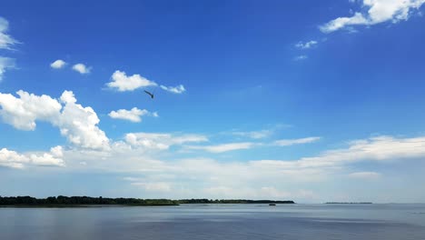 colorful spring summer landscape on river with beautiful clouds in the sky, shooting from a car that goes on the road along the water, dynamic scene, 4k video.