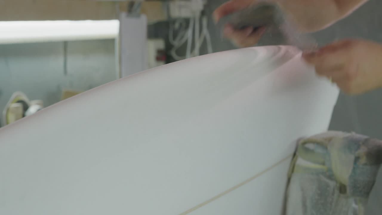 мужчина, делающий доски для серфинга, в своей мастерской