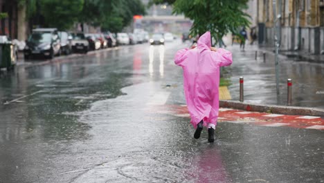 woman in pink raincoat walking through a flooded city street